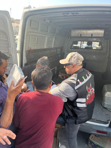 A worker receives an iftar packet from a member of the biker group
